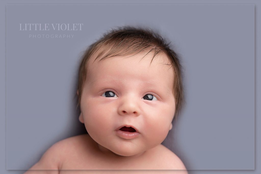 cute smiley baby looking up eyes open on grey background