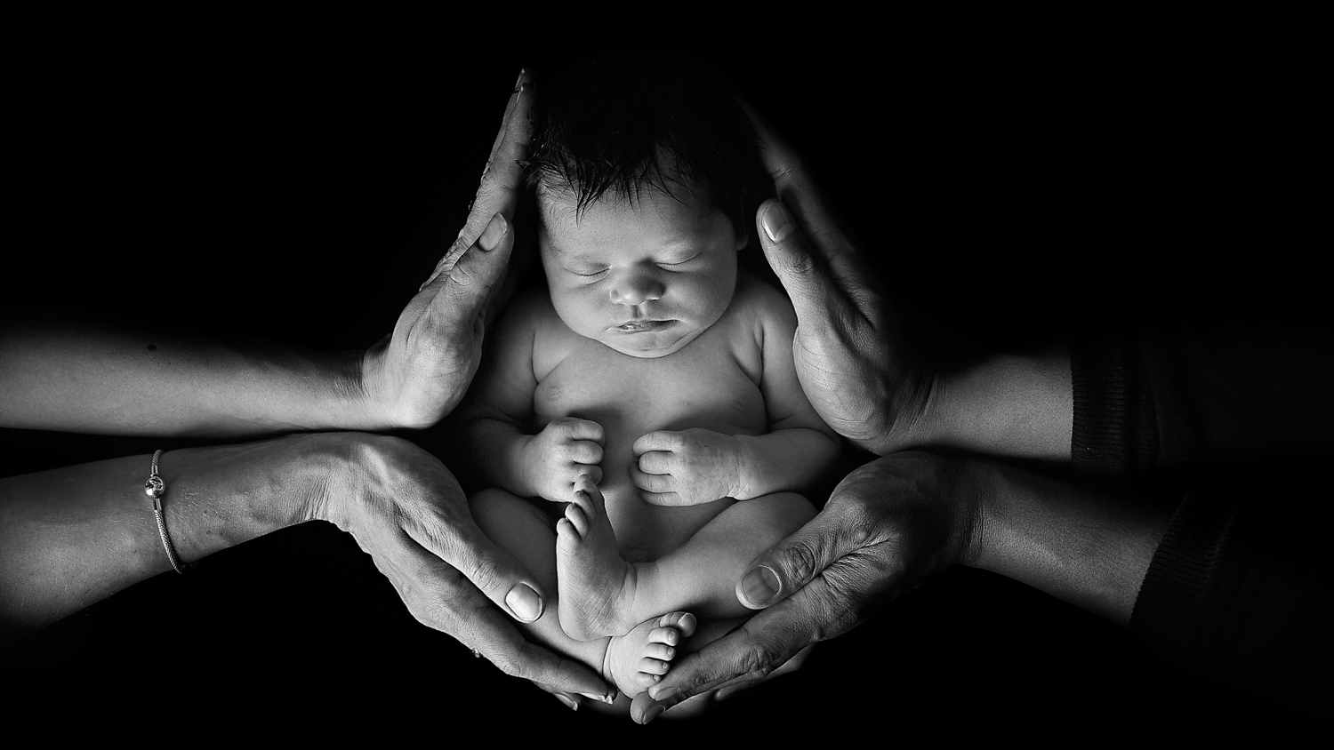newborn photographer ipswich baby in parents hands black and white